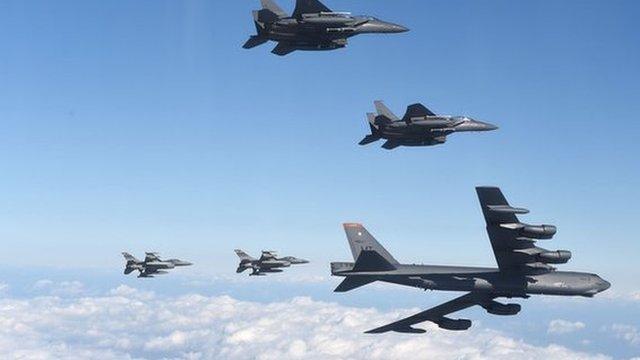 A US B-52 bomber in flight flanked by fighter jets