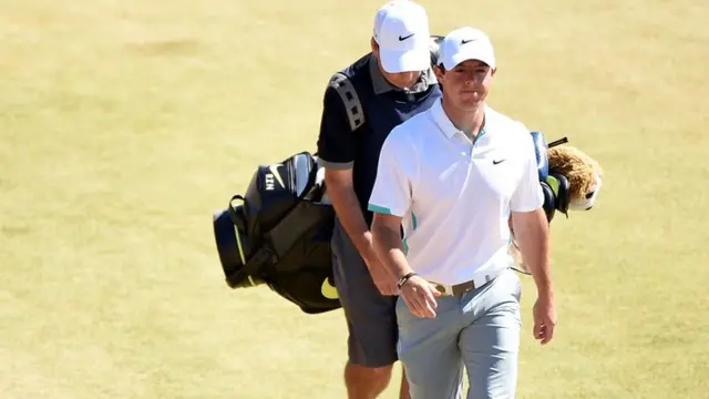 Rory McIlroy smiles whilst walking with his caddie