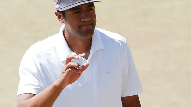 Tony Finau holds up his ball