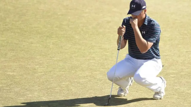 Jordan Spieth crouches on the green