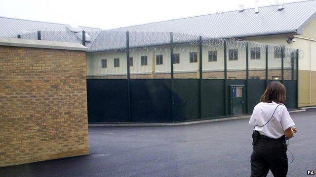 File photo of prison officer walking past fencing Yarl's Wood detention centre in Bedfordshire