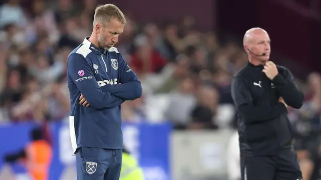 Graham Potter has his arms crossed and head down
