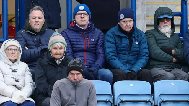 A group of disappointed Leicester City supporters watching their team lose to Charlton