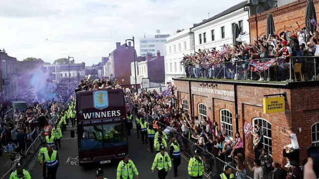 Fans greet the team bus from a balcony during the Aston Villa trophy parade