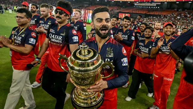Royal Challengers Bengaluru's Virat Kohli (C), along with his teammates, takes a victory lap around the field as he celebrates with the trophy after winning the Indian Premier League (IPL) Twenty20 final cricket match against Punjab Kings at the Narendra Modi Stadium in Ahmedabad 