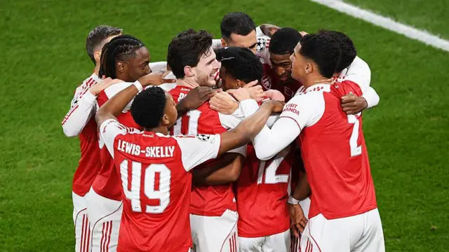 Arsenal players all celebrate together in a huddle