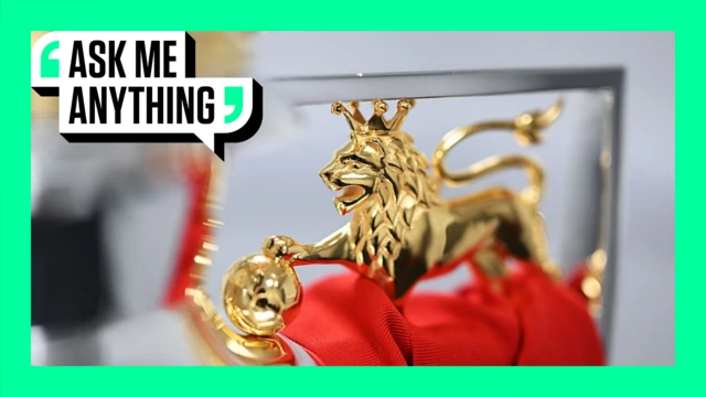 A close-up of the Premier League trophy with the gold lion surrounded by a green border and the words Ask Me Anything