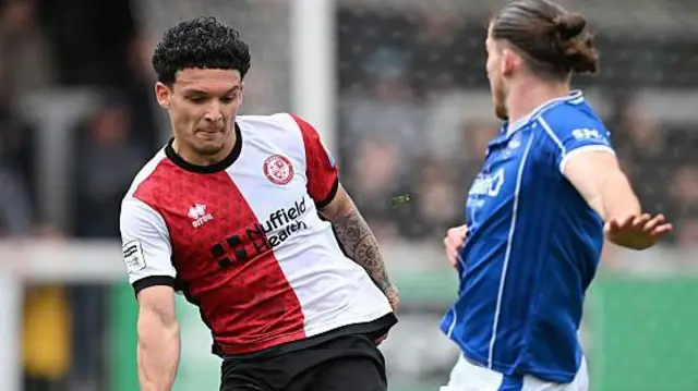 Aaron Drewe of Woking in red and white halved shirt playing against Eastleigh in blue