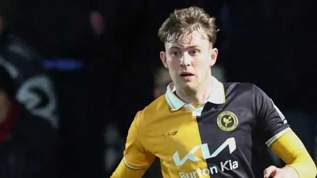 JJ McKiernan playing for Burton Albion in a gold and black shirt