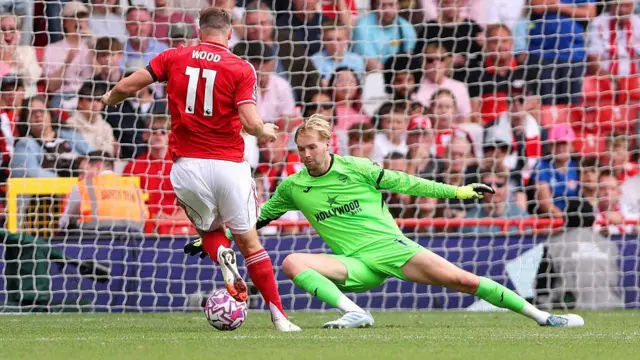 Chris Wood of Nottingham Forest goes around goalkeeper Caoimhin Kelleher of Brentford to score his team's third goal during the Premier League match between Nottingham Forest and Brentford at City Ground 
