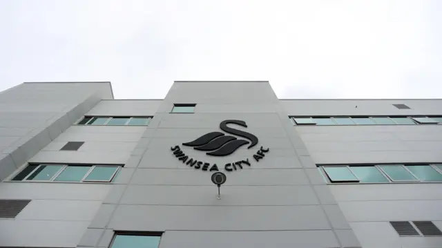 Upward looking image of the Swansea.Com Stadium west stand reception front with club badge