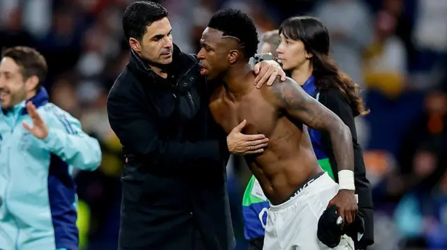 Mikel Arteta and Vinicius Junior embrace after a Champions League game between Real Madrid and Arsenal