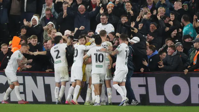 Swansea City players celebrate in a huddle in front of home fans at Swansea.Com Stadium