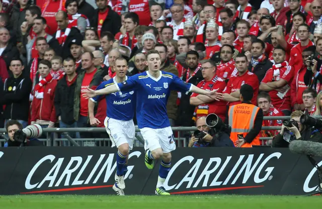 Joe Mason with arms outstretched followed by Kenny Miller as they celebrate Cardiff's goal with Liverpool fans in background