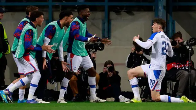 Strand-Larsen slides and celebrates a goal for Crystal Palace as his substitute team-mates wait to mob him