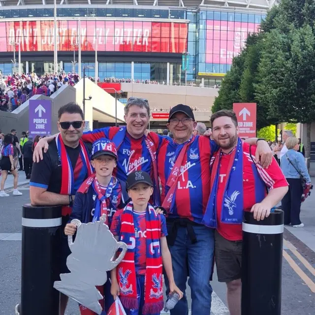 Picture of four grown up men and two children draped in Crystal Palace kits and scarves outside Wembley for the FA Cup