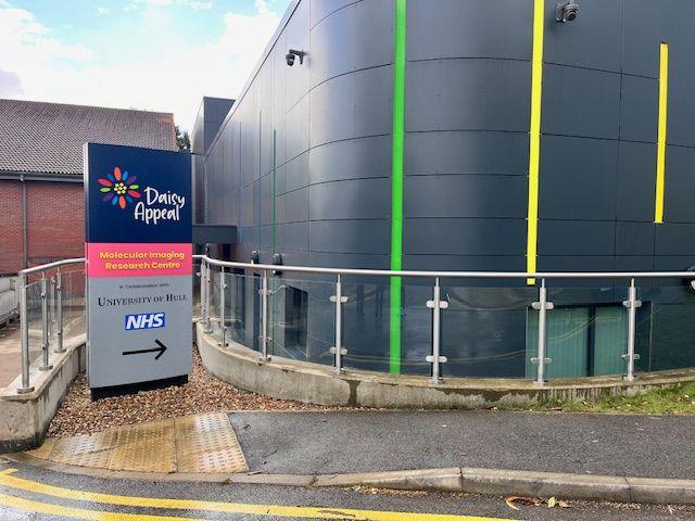 The exterior of the Molecular Imaging Research Centre at Castle Hill Hospital. The building is covered in dark grey cladding and has colourful stripes as part of the design.