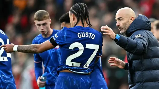 Chelsea's Italian head coach Enzo Maresca listens to Chelsea's French defender #27 Malo Gusto during the English Premier League football match between Liverpool and Chelsea at Anfield