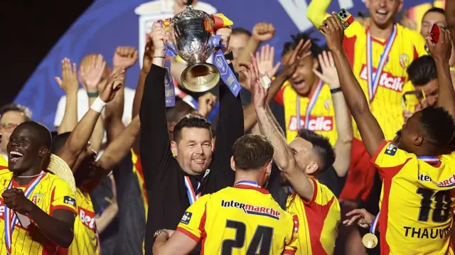 Former coach of RC Lens Pierre Sage and his players celebrate during the trophy ceremony following the French Cup Final 
