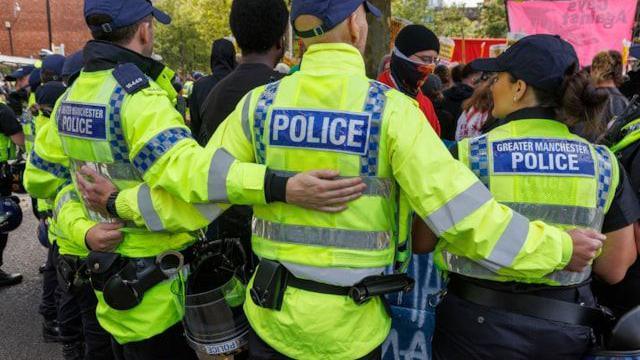 Officers from Greater Manchester Police form a ring around protesters at Piccadilly Gardens 