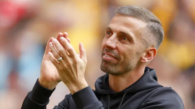 Gary O'Neil looks upwards with raised hands and applauds the fans while wearing a dark hoodie 