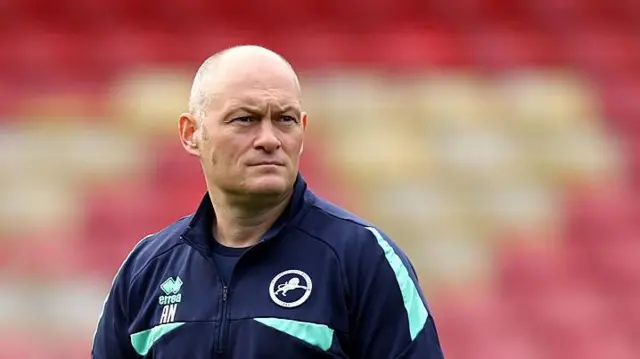 Alex Neil watches Millwall's warm up on the pitch