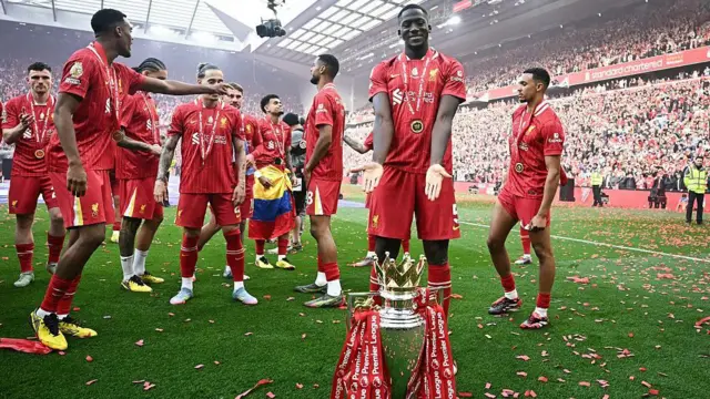 Konate points to the Premier League trophy which sits on the Anfield turf