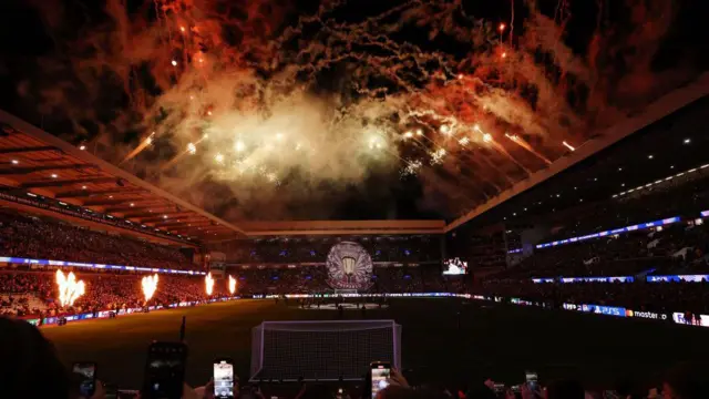 Three sides of Villa Park, with the pitch in darkness and the surrounds lit up with pyros and a tifo before a Champions League game