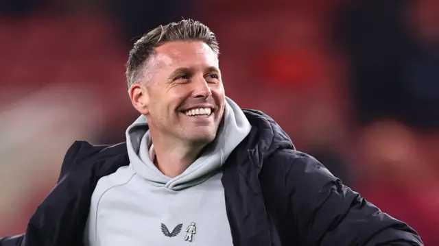 Rob Edwards, smiling and wearing a grey hooded top and a black jacket