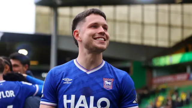 George Hirst smiling in his blue Ipswich Town home kit after the side sealed promotion last season