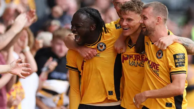 Kai Whitmore (centre) of Newport County celebrates with Shane McLoughlin (right) and Cameron Antwi (left).