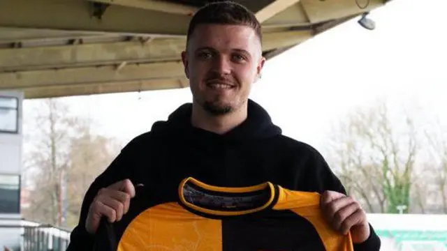 Cole Jarvis holding up a Newport County shirt