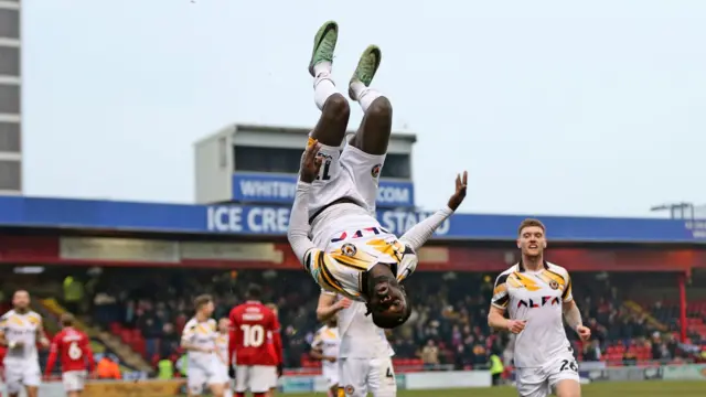 Cameron Antwi in mid-air celebration after scoring for Newport at Crewe