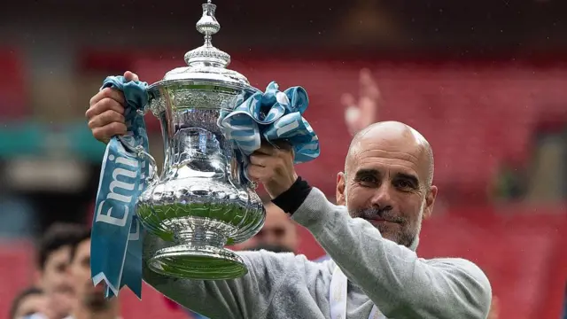Manchester City manager Pep Guardiola celebrates with the FA Cup trophy 