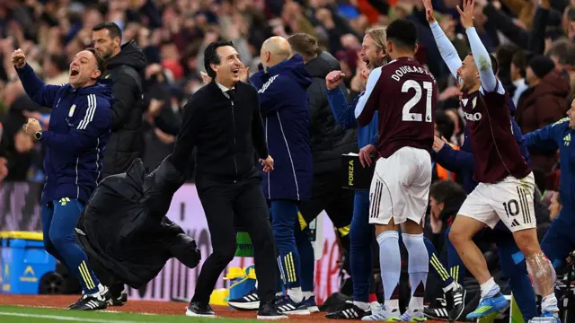 Unai Emery takes off his coat as he and the Aston Villa bench celebrate