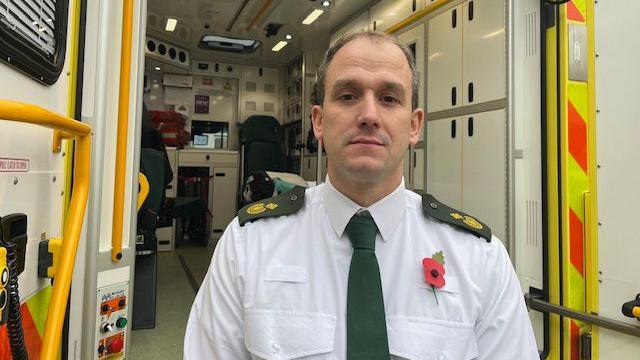 Associate chief ambulance officer, Gordon Hunt, in front of ambulance in a shirt and tie.