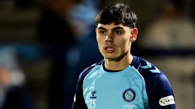 Declan Skura in action for Wycombe wearing a home shirt of sky blue front with dark blue sleeves.