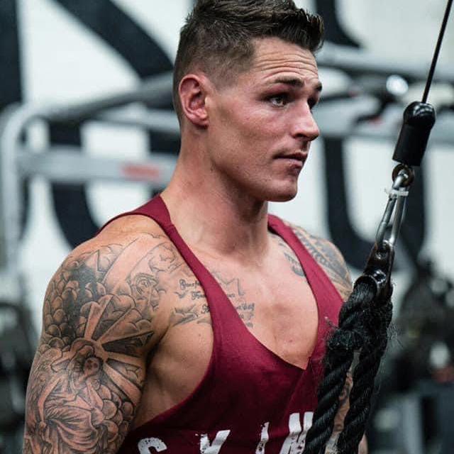 A muscular man in a gym wearing a skimpy red top, doing some pulling exercises