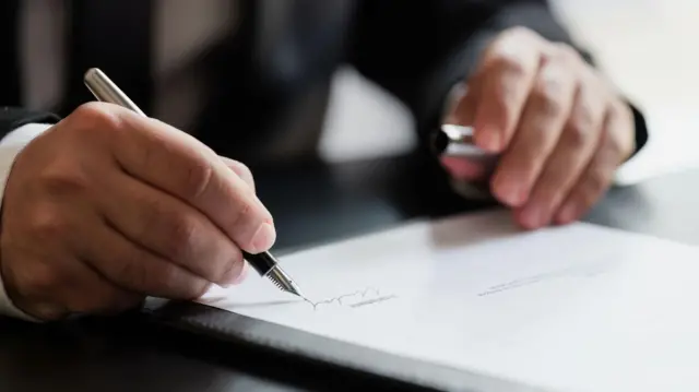 Stock image of a man signing a contract