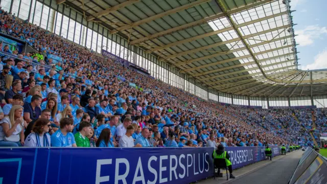 Fans sit inside Coventry City's CBS Arena looking out to the pitch