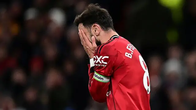 Bruno Fernandes holding his face with his hands in dejection