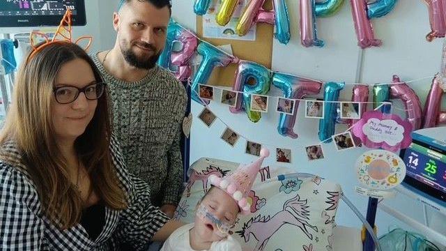 Robyn under a Happy Birthday banner with her parents