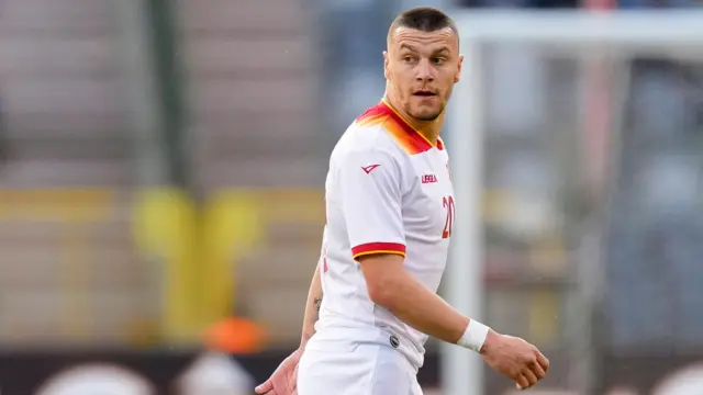 A close-up of Milutin Osmajic playing for Montenegro in the side's white away kit