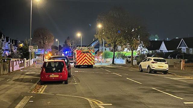 A fire engine driving down the middle of a road at night