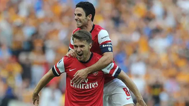 Mikel Arteta jumps on Aaron Ramsey's back in celebrating an Arsenal goal in 2014