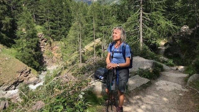 A LADY WALKING ON A HILLSIDE IN A BLUE TOP