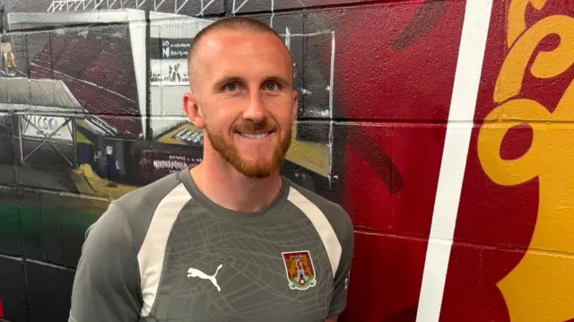 Conor Lemonheigh-Evans poses in a Northampton Town training kit at Sixfields Stadium.