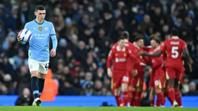 Phil Foden looks dejected while Liverpool players celebrate