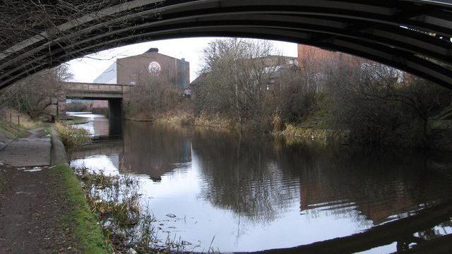 Tinsley Canal in the Darnall area of Sheffield on an overcast day. There's a towpath next to the canal and a factory on the other side of the water.
