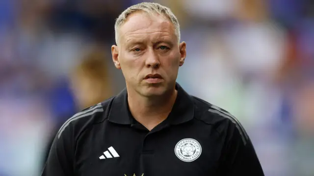 Steve Cooper looks at the camera while wearing a black Leicester shirt with their badge on the left of his chest and the Adidas logo on the right